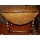 An oak low drop-flap occasional table, raised on turned and square cut supports, width 61cm