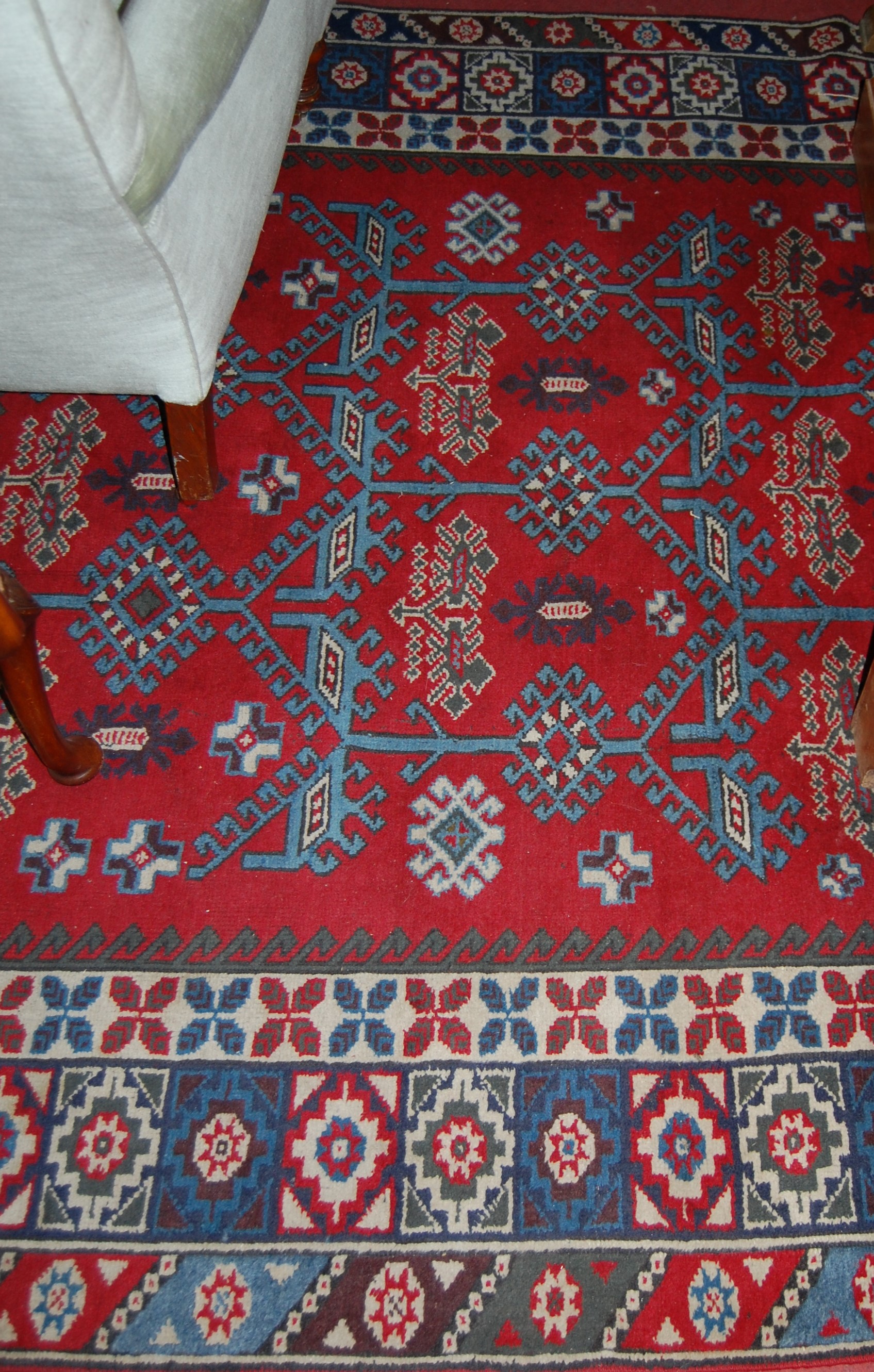 A Turkish woollen red ground rug, having a typical geometric floral decorated ground within trailing