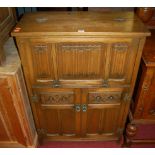 A contemporary Old Charm linenfold moulded oak drinks cabinet, having a twin hinged upper