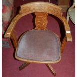 A 1930s oak tub swivel elbow desk chair, having fabric and studded fixed pad seat, width 58cm