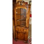 An early Georgian style figured walnut free standing corner cupboard, the architectural pediment
