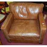 A good contemporary tan leather upholstered and brass studded club armchair, raised on tapering