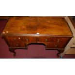 A 1930s figured walnut kneehole four drawer dressing table raised on cabriole supports, width 107cm