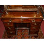 A small Georgian style mahogany kneehole desk, having an arrangement of seven drawers with central