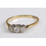 An 18ct gold and platinum diamond set three-stone ring, the round cut diamonds in a line setting,