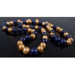 An opera length pearl and lapis lazuli necklace, featuring thirty-three approx 12.2mm spherical