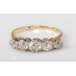 A yellow metal diamond five-stone ring, the graduated claw set round cut diamonds in a line setting,