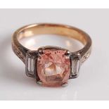 A yellow and white metal, pink sapphire and diamond ring, featuring an oblong pink sapphire with a