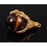 A 9ct yellow gold pendant in the form of a claw holding a tiger's eye bead, tiger's eye diameter