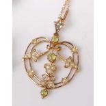 An Edwardian yellow metal, green peridot and seed pearl set openwork pendant, comprising three round