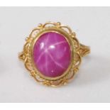 A 9ct gold 'synthetic' pink star sapphire set dress ring, the cabochon stone measuring approx 12 x 9