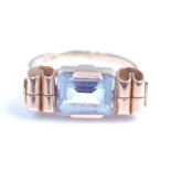 A yellow metal and blue topaz set dress ring, the step cut blue topaz in a horizontal bar setting,