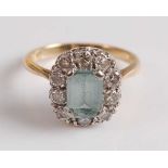 A yellow and white metal, aquamarine and diamond rectangular cluster ring, featuring an emerald