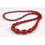 A single row necklace of 54 graduated oval cherry amber beads with integral clasp, length 680mm,