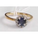 An 18ct gold, sapphire and diamond cluster ring, arranged as a four-claw set oval cut sapphire