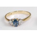 A modern 18ct gold, sapphire and diamond three-stone ring, the four claw set oval cut sapphire