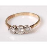 A yellow and white metal diamond three stone ring, the graduated round brilliant cut diamonds in
