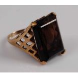 A 9ct yellow gold smoky quartz dress ring featuring a rectangular cut smoky quartz in a four-claw