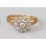 A yellow metal diamond flowerhead cluster ring, arranged as a three-tiered setting of small