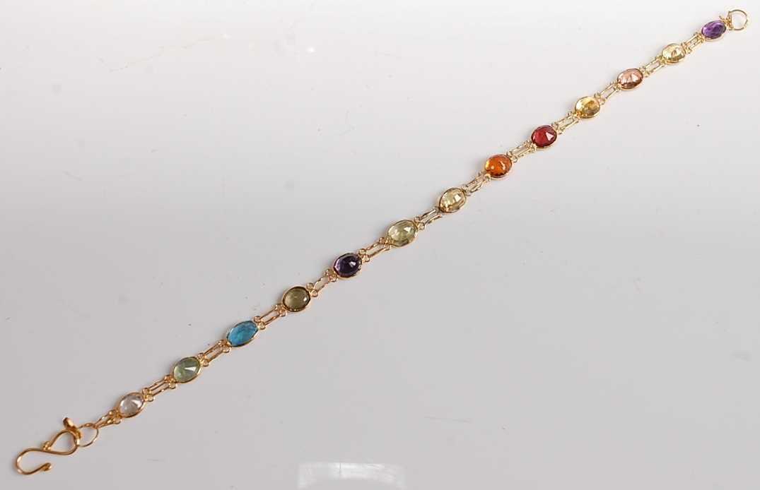 A yellow metal multi-stone bracelet, featuring amethyst, citrine, topaz, garnet, peridot, blue topaz