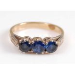 A yellow and white metal sapphire three stone ring, featuring three graduated round faceted