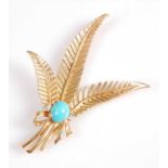 A yellow metal triple feather brooch, featuring an oval cabochon cut turquoise flanked to either
