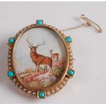 A yellow metal oval painted miniature brooch depicting a stag and fawn, within a border of six round