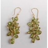 A pair of yellow metal peridot multi-stone drop earrings, each comprising fourteen oval faceted