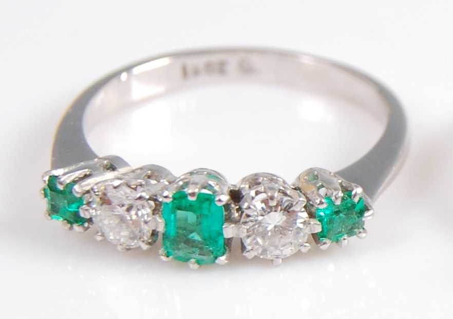 A white metal, emerald and diamond five stone half hoop eternity ring, featuring three graduated