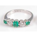 A white metal, emerald and diamond five stone half hoop eternity ring, featuring three graduated
