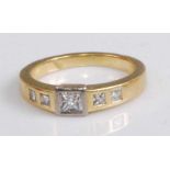 An Art Deco style yellow metal diamond set ring, arranged as a raised centre Princess cut diamond