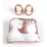 A yellow metal carved shell cameo brooch and earring suite, the trapeze shaped brooch measuring 50 x