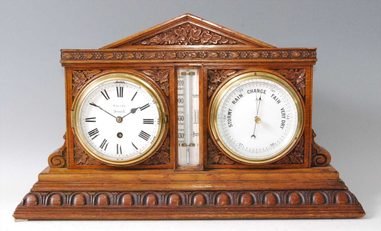 A Victorian carved oak desk weather station, inset with clock and barometer, with central