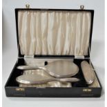 A cased engine turned silver backed three-piece dressing table set, comprising hairbrush, clothes