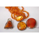 A faux orange amber multi-string necklace with clear amber pendant; together with a silver mounted