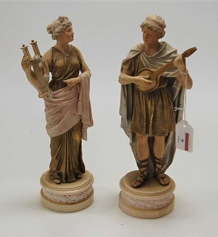 A pair of Royal Dux type porcelain musician figures, each heightened with gilt enamels and on