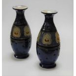 A pair of Doulton Lambeth stoneware vases, having incised leaf decoration on blue ground (one a/