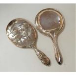 A late Victorian silver backed dressing table hand mirror, decorated with winged cherubs; together