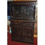 A late 19th century heavily carved and ebonised narrow oak court cupboard, the twin upper doors