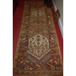 A Persian woollen brown ground hall runner, having hexagonal trailing central motifs within borders,
