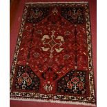 An Iranian woollen red ground rug, the central ground decorated with four stylised doves, within
