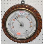 A 1920s oak ropetwist framed circular single dial aneroid barometer, dia.26cm