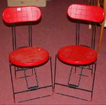 A set of four contemporary Italian red polypropylene and black painted tubular metal folding cafe