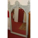 A large contemporary grey painted arched and bevelled overmantel mirror, having floral carved and