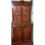 A William IV mahogany and flame mahogany bookcase cupboard, the castle-top cornice over twin