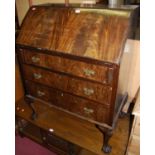 A 1920s mahogany and flame mahogany slopefront three drawer writing bureau, raised on shell capped