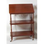 A late Victorian mahogany three-tier whatnot, having a hinged lectern top and raised on slender