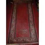 A Persian woollen red ground rug, 210 x 110cm; together with a further red ground woollen rug with