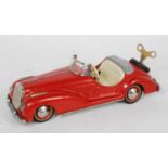 A Distler(?) tinplate and clockwork model of an open-top two seater saloon, comprising red body with