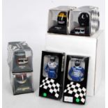 A collection of Minichamps and Amalgam miniature F1 driver figures, helmets, and resin nose cones,
